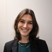 Hannah Ehrlich portrait head shot smiling in front of white wall